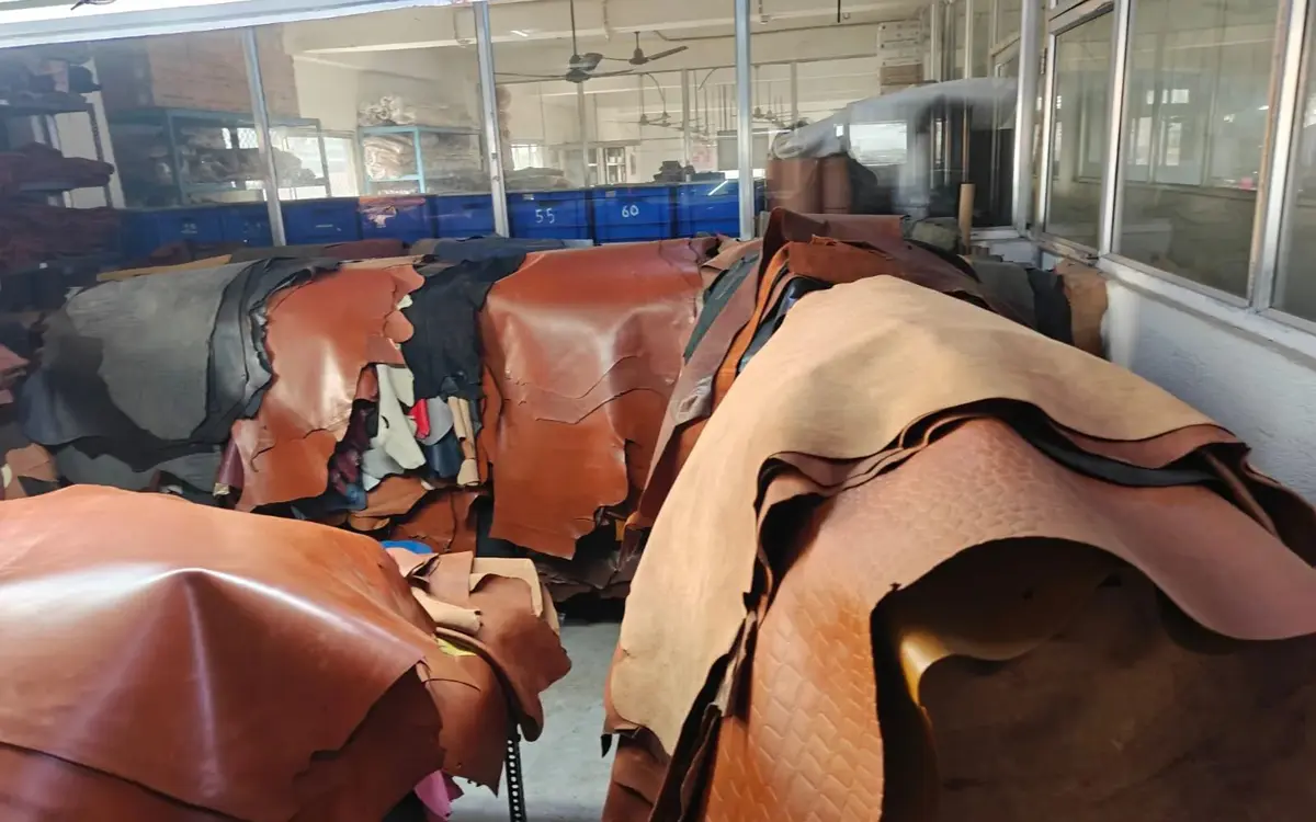 Tan and brown full hides stacked on racks in the hide store
